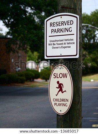 Signs in a parking lot, warning of authorized parking only and children at play.