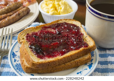 toast with berry jam enjoyed with morning coffee,sausage and bacon \