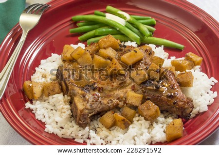 pork chops on a bed of rice with caramelized apple topping served with fresh green beans 