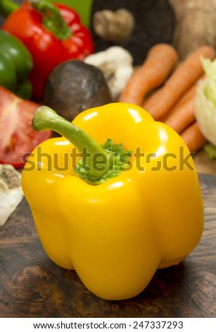 yellow bell pepper on cutting board in front of assortment of fresh salad ingredients\