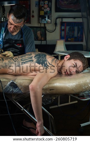 Tattooed man lying on the table in tattoo studio