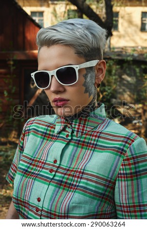 Outdoor vintage Portrait of tattooed blonde young Female with green Dress and white Sunglasses