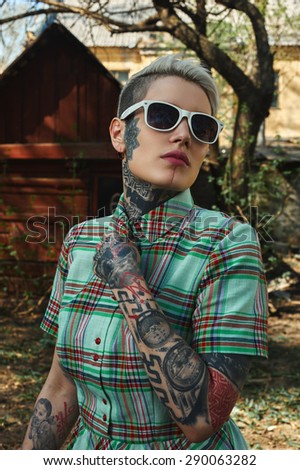 Vintage Portrait of tattooed blonde Female with white Sunglasses, unbuttoned her Dress