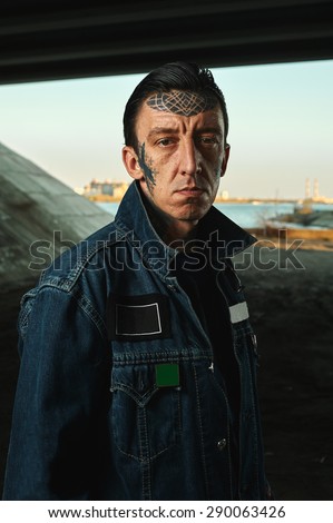 Outdoor Portrait of Man with tattooed Face in denim Jacket on Street