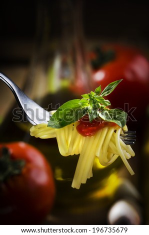 Spaghetti, tomato sauce and basil on fork