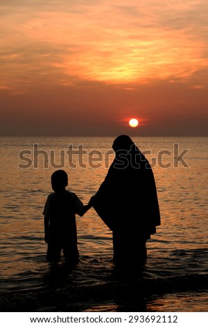 Muslim woman and son  walking during sunset silhouette