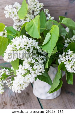White lilac flowers in the vase on the old wooden table