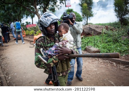 Nairobi, Kenya - February 13, 2014: A Kenyan riot police officer carries a baby during a protest.