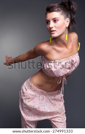 young beautiful woman in a dynamic pose brown hair in a pink top on a gray background