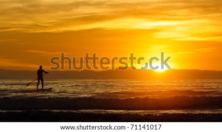 lone paddle board surfer at sunset