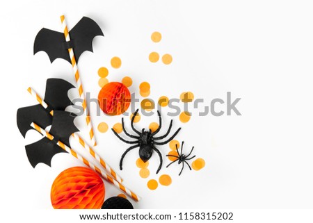 Halloween holiday decorations. Striped straws with paper bats and confetti , spiders  on white background. Flat lay, top view
