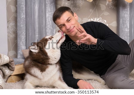 Husky dog licks cheek handsome man