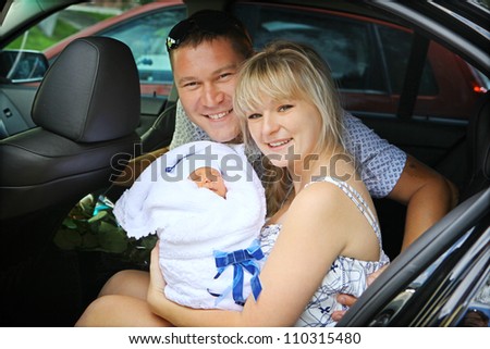 Happy family with newborn in car