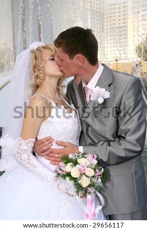 Bride and groom kissing near fountain