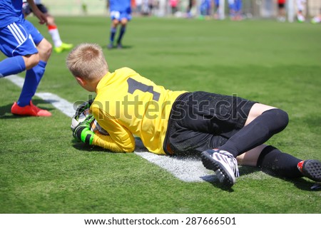 Goalkeeper catching ball and falling on grass