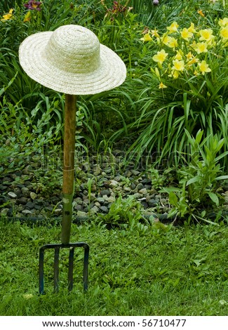 gardening fork and straw hat with a background of flowers