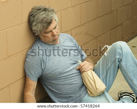 homeless man with his bottle passed out in an alley