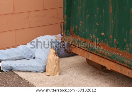 drunk man passed out behind a dumpster