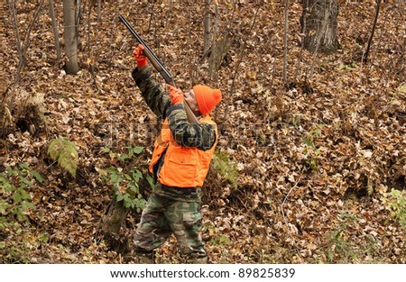 hunter aiming his weapon in the autumn woods