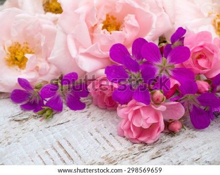 Pale pink and small bright pink roses and geranium bouquet on the white rough wooden table