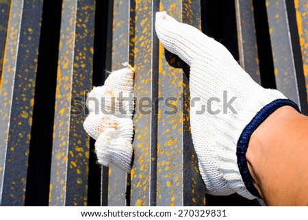 Safety a hand by white glove for working time of labor,workman with bundle bars,iron ready for construction.Focus on a white glove and iron in a hand