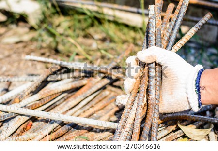 Safety a hand by white glove for working time of labor,workman with bundle bars,iron ready for construction.Focus on a glove and iron in a hand
