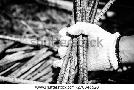 Safety a hand by white glove for working time of labor,workman with bundle bars,iron ready for construction.Focus on a glove and iron in a hand with black and white color