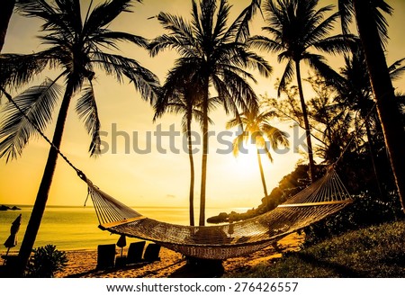 Time to relax with silhouette of hammock and coconut tree at the beach on sunset time in Samui Island Thailand