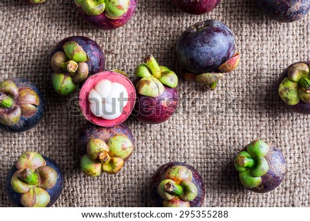 Mangosteen and cross section showing the thick purple skin and white flesh of the queen of friuts, Delicious mangosteen fruit arranged on a hemp sack background, Mangosteen flesh, top view