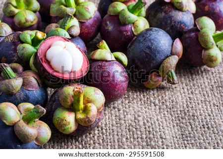 Mangosteen flesh and cross section showing the thick purple skin and white flesh of the queen of friuts, Delicious mangosteen fruit arranged on a hemp sack background.
