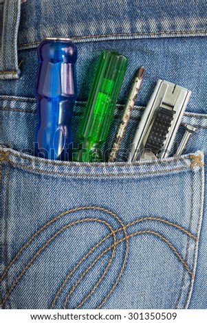Close-up of old screwdriver green and cutter in Blue Jeans Pocket.
