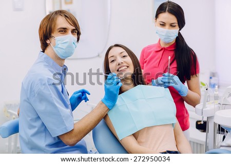 Two professional doctors treat teeth beautiful woman