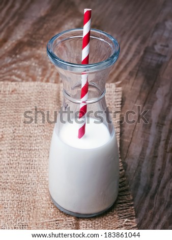 A bottle of organic natural milk and red striped paper straw