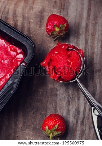 Scoop of strawberry sorbet on the wooden table. Filtered photo
