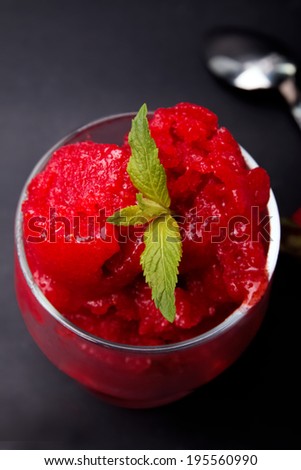 Strawberry sorbet in a glass on the black backrground close up