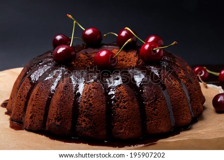 Delicious chocolate cake with glaze and cherries on the black background