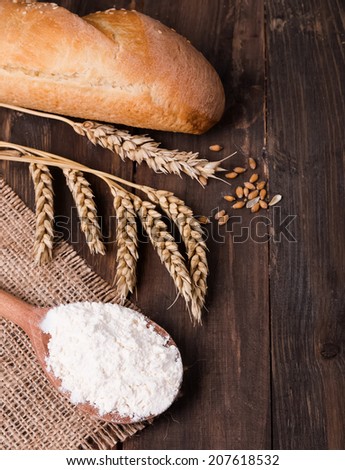 Ears of wheat, flour and bread on the wooden table