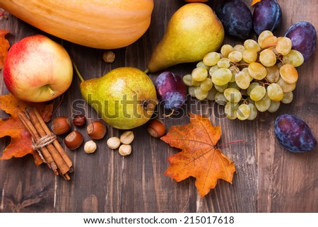 Autumn harvest. Pears, apple, grapes and yellow leaves on the wooden table