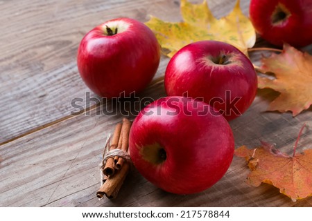 Red apples and yellow leaves on the wooden table