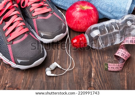 Sport equipment. Sneakers, water and earphones on wooden background