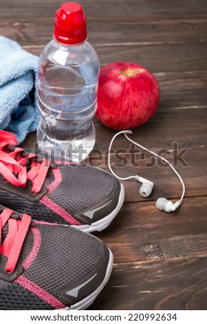 Sport equipment. Sneakers, water and earphones on wooden background