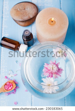 Spa still life. Vase with flowers, candle, sea salt, bottles and stones.