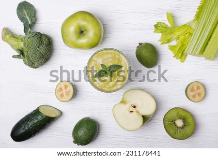 Green colored fruits and vegetables on the white wooden table, top view