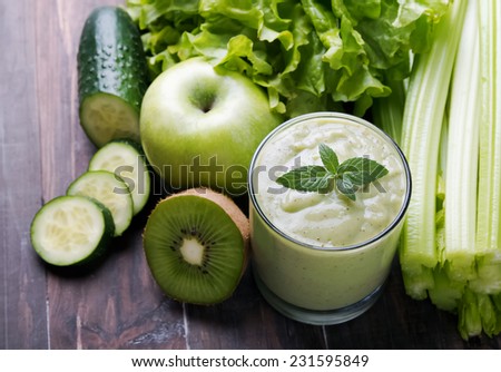 Healthy green smoothie and green vegetables and fruits on the wooden table