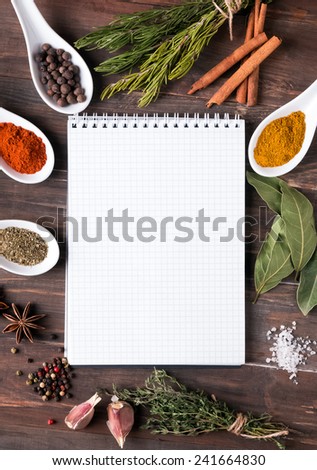 Fresh herbs, different spices and empty notebook on the wooden table
