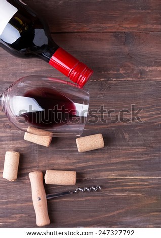 Bottle of wine, wine glass, corks and corkscrew on the wooden background, top view