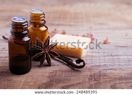 Bottles with aroma oil, vanilla pods and hand made soap on the wooden background close-up