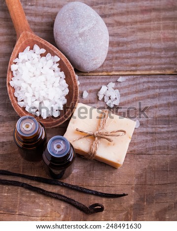 Spa still life on the wooden background, top view. Hand made soap, vanilla pods, aroma oils and sea salt.
