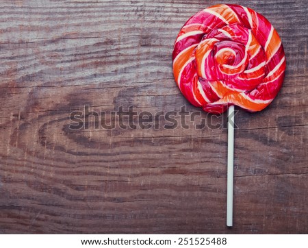 Red round lollipop on the wooden background, dark toned photo