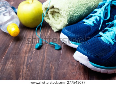 Sport equipment close-up. Sneakers, water, towel and earphones on the wooden background